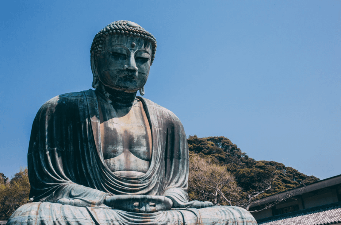 Estàtua del Gran Buda de Kamakura a l’aire lliure, imponent figura de bronze envoltada de visitants i natura.