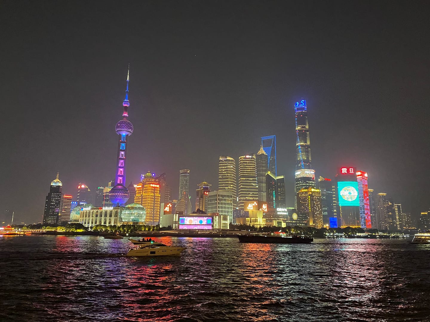 Panoràmica nocturna del Bund de Shanghai amb edificis il·luminats i reflexos sobre el riu Huangpu