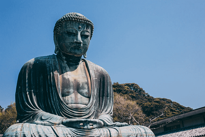 Estàtua del Gran Buda de Kamakura a l’aire lliure, imponent figura de bronze envoltada de visitants i natura.