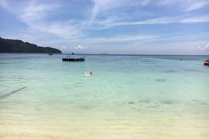 Vista d’una platja tropical a Perhentian Besar amb palmeres, sorra blanca i mar cristal·lí