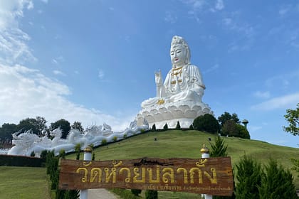 Estàtua gegant de Guan Yin al temple Wat Huay Pla Kang de Chiang Rai, envoltada de paisatge verd i cel clar