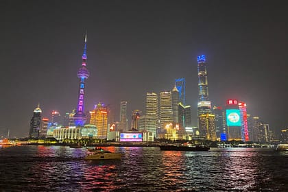 Panoràmica nocturna del Bund de Shanghai amb edificis il·luminats i reflexos sobre el riu Huangpu