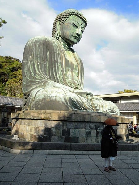 Gran Buda de Kamakura a l’aire lliure, estàtua monumental de bronze envoltada de visitants i natura.
