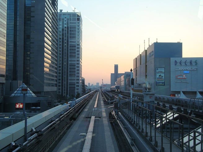Vista nocturna de Minato Mirai des del monorail, amb gratacels il·luminats i la nòria de Cosmo World al fons.