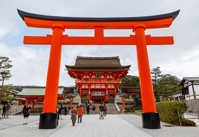 Entrada de Fushimi Inari Taisha amb el gran torii vermell i el santuari principal Honden al fons.