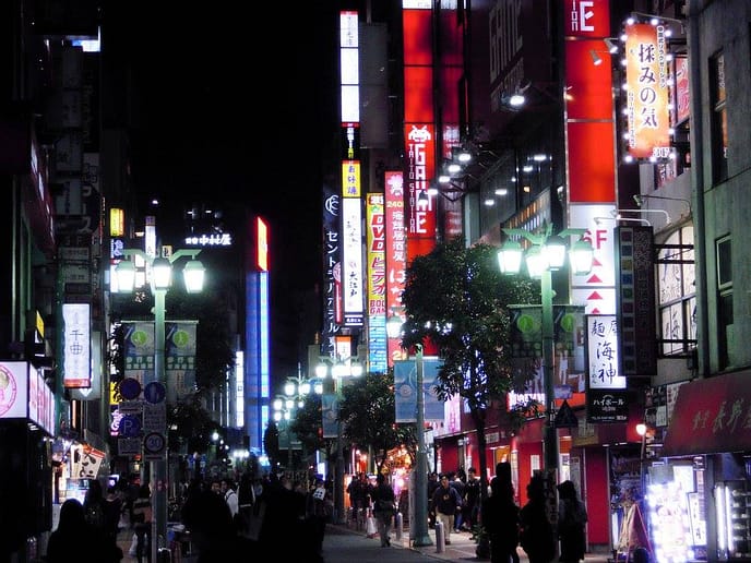 Carrer nocturn de Kabukichō, a Shinjuku, amb rètols de neó i vianants caminant entre locals il·luminats.