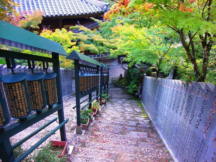 Escales de pedra del Daishō-in a Miyajima amb fileres de molinets budistes metàl·lics que giren al llarg del camí.