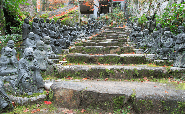 Escales de pedra del temple Daishō-in a Miyajima, flanquejades per centenars de molinets budistes i envoltades de vegetació.