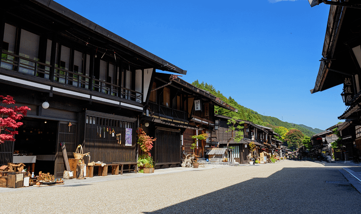 Poble tradicional del Nakasendo de dia amb cases de fusta i cel blau clar.