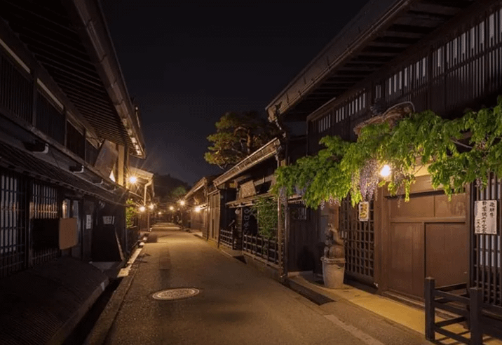 Carrer tradicional de Takayama de nit, amb fanalets japonesos i façanes de fusta il·luminades.