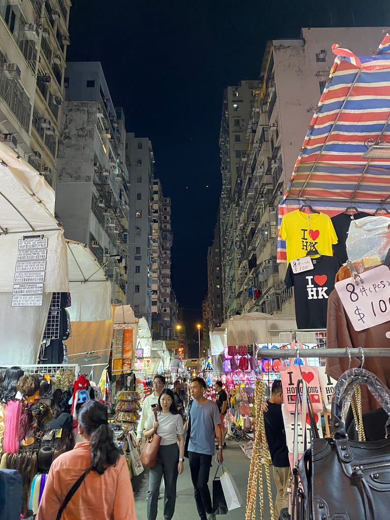 Fotografia nocturna de Temple Street a Hong Kong, amb parades de mercat, llums de neó i vianants