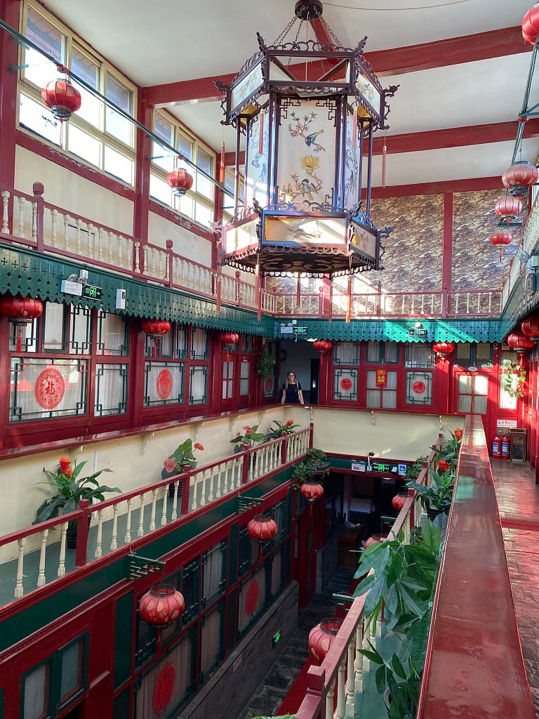Vista de l’interior d’un hotel amb arquitectura tradicional, pati central amb vegetació i mobiliari rústic