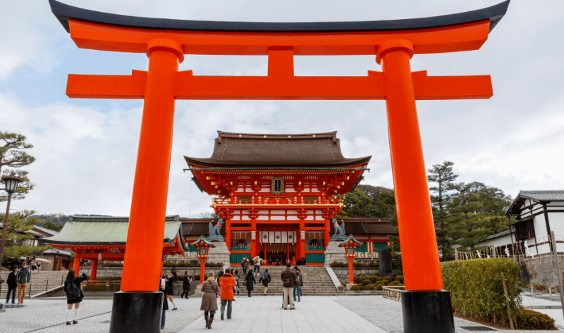 Entrada de Fushimi Inari Taisha amb el gran torii vermell i el santuari principal Honden al fons.
