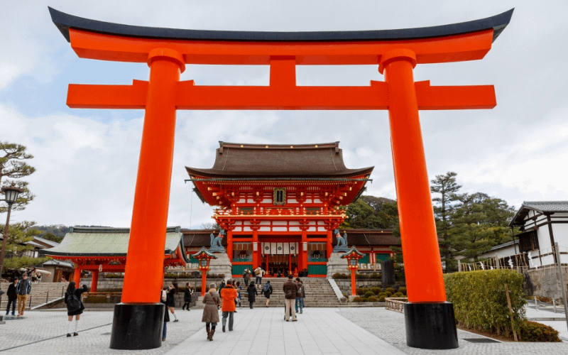 Entrada de Fushimi Inari Taisha amb el gran torii vermell i el santuari principal Honden al fons.