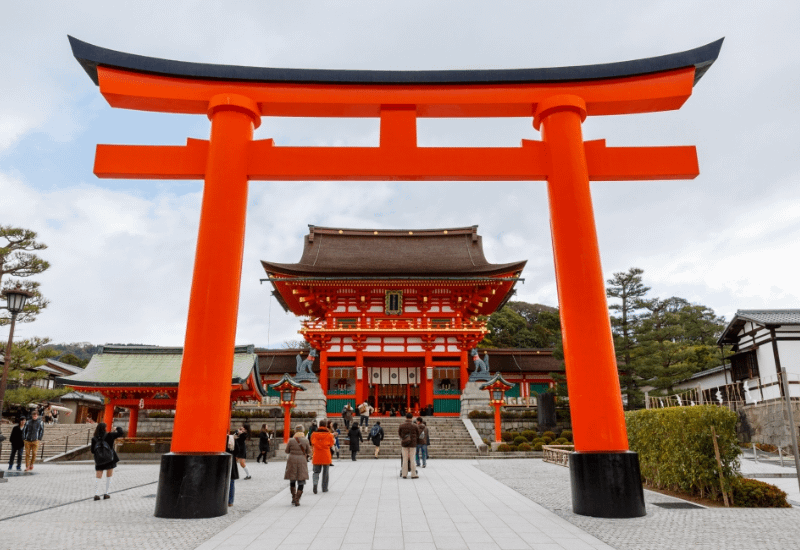 Entrada de Fushimi Inari Taisha amb el gran torii vermell i el santuari principal Honden al fons.