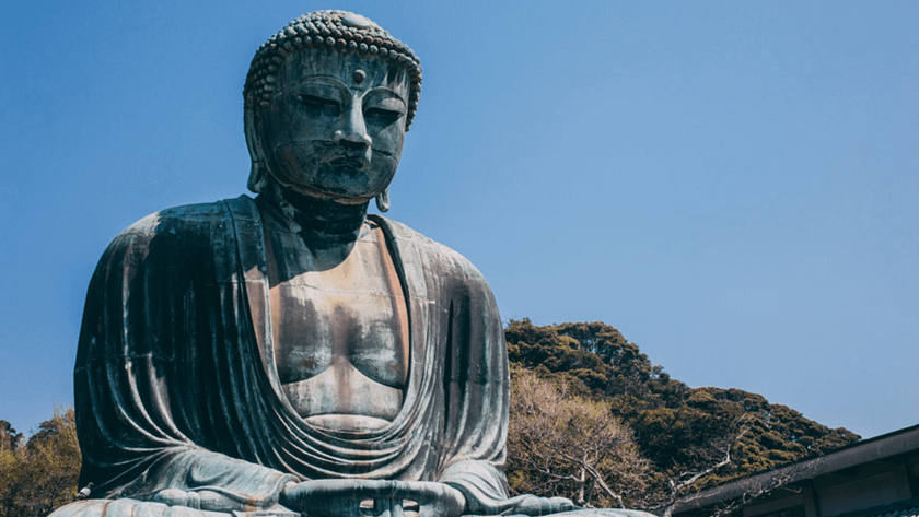 Estàtua del Gran Buda de Kamakura a l’aire lliure, imponent figura de bronze envoltada de visitants i natura.