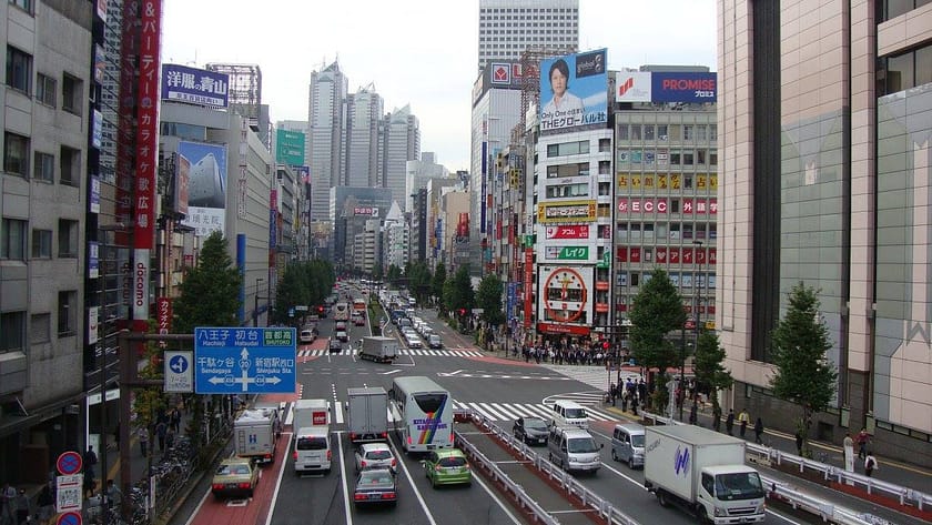 Vista urbana de Shinjuku amb trànsit, gratacels i cartells lluminosos des del pont de vianants.