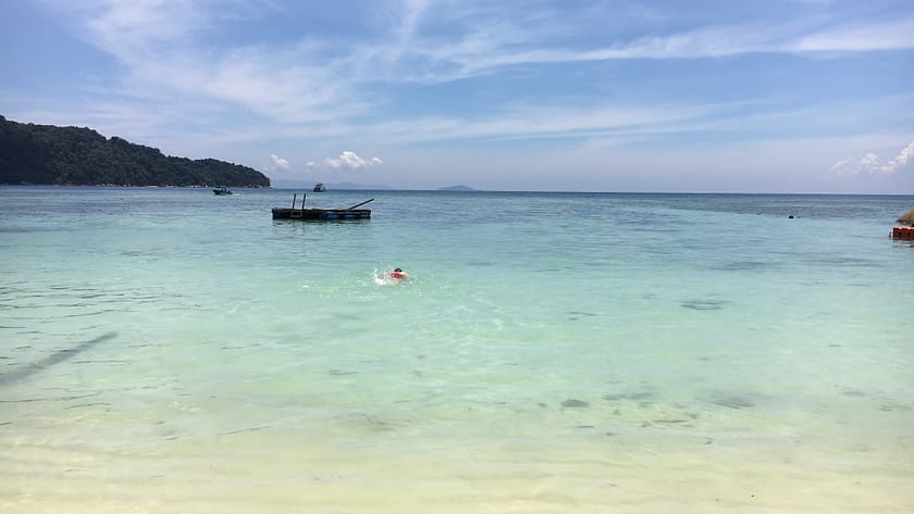 Vista d’una platja tropical a Perhentian Besar amb palmeres, sorra blanca i mar cristal·lí