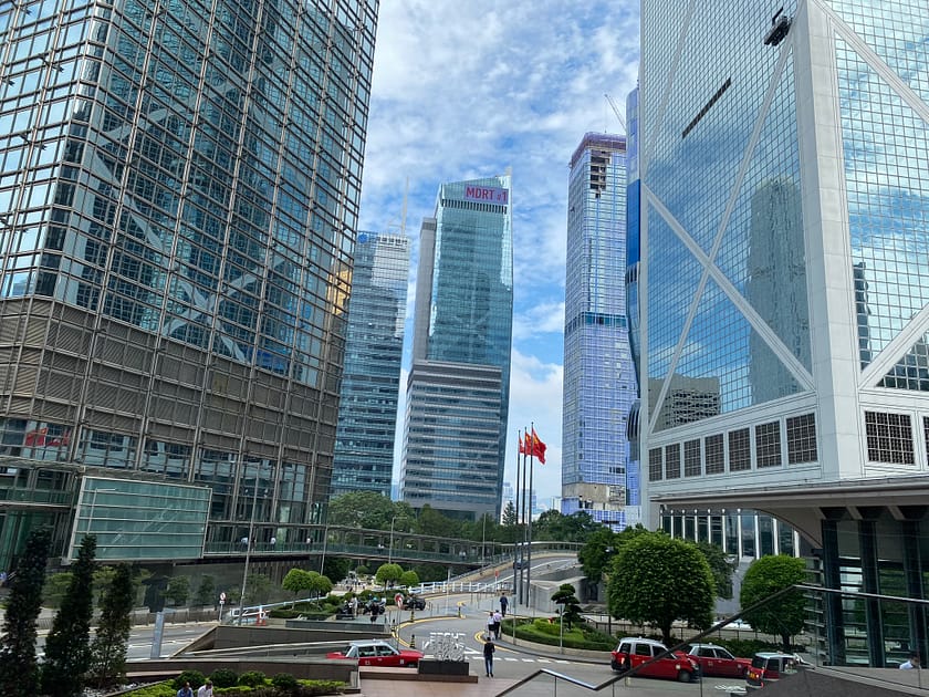 Fotografia de carrers de Hong Kong amb gratacels al fons, trànsit urbà i vianants