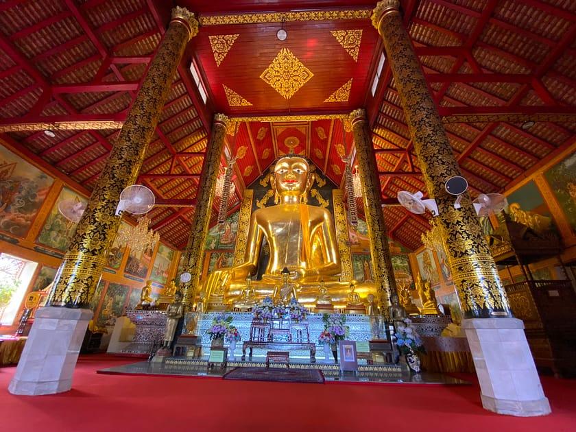 Interior del temple Wat Jed Yod a Chiang Rai amb estupa blanca i decoració tradicional envoltada de vegetació