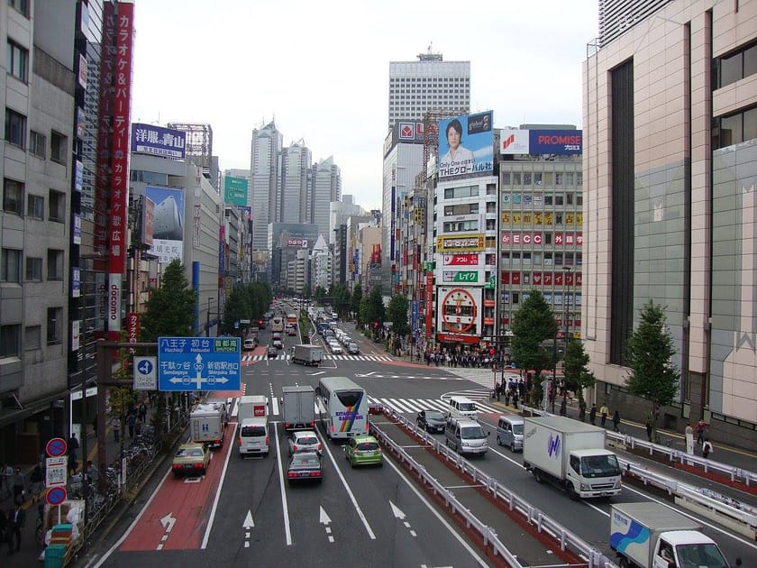 Vista urbana de Shinjuku amb trànsit, gratacels i cartells lluminosos des del pont de vianants.