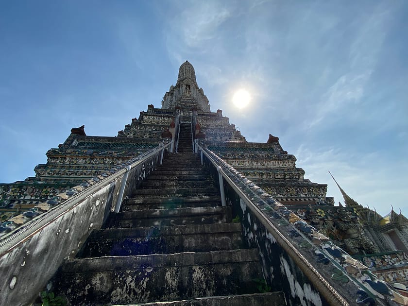 Torre del Wat Arun amb el sol al darrere en un dia a Bangkok