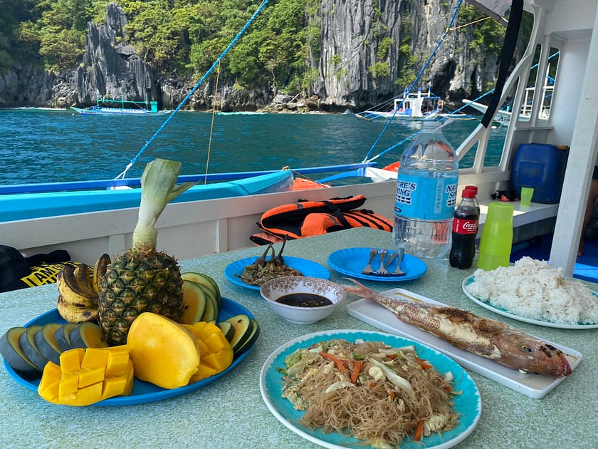 Dinar típic filipí servit a bord d’una bangka durant l’island hopping a El Nido, amb peix fresc, arròs i fruita tropical.