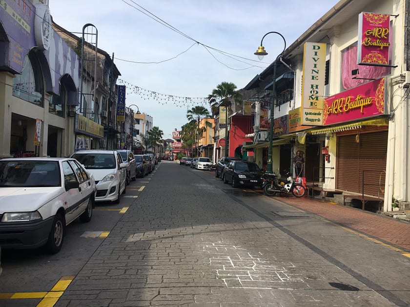 Carrer de George Town amb edificis antics, motos aparcades i vida local