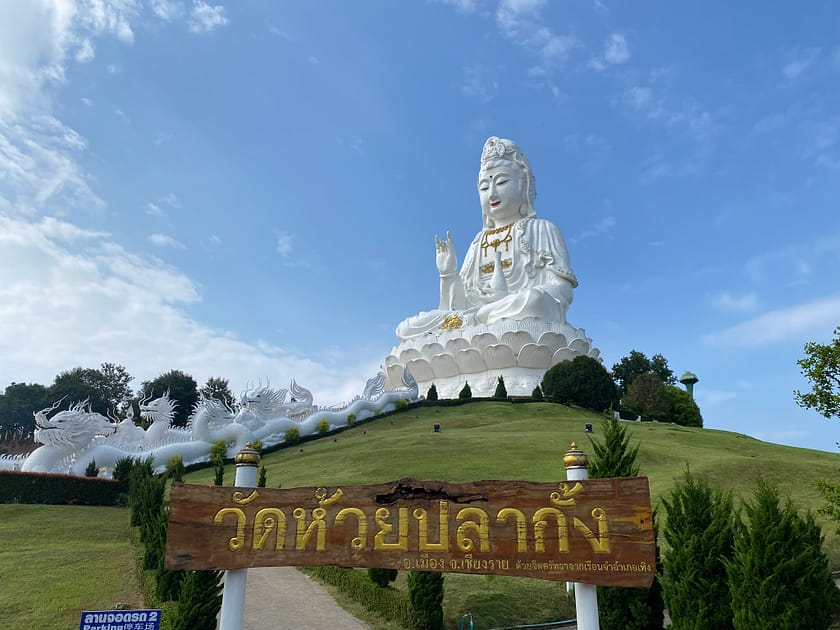 Estàtua gegant de Guan Yin al temple Wat Huay Pla Kang de Chiang Rai, envoltada de paisatge verd i cel clar