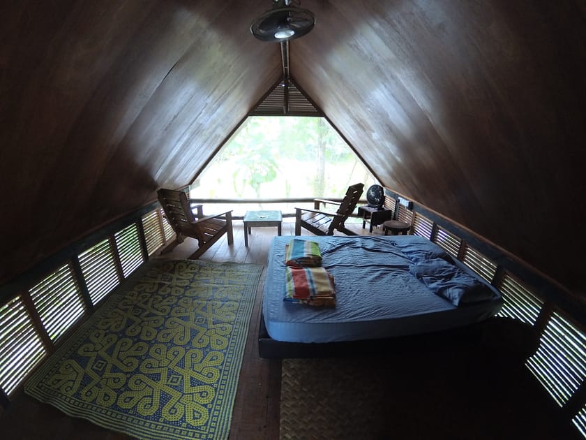 Interior d’una cabana tradicional a Sumbiling Eco Village, envoltada de natura tropical