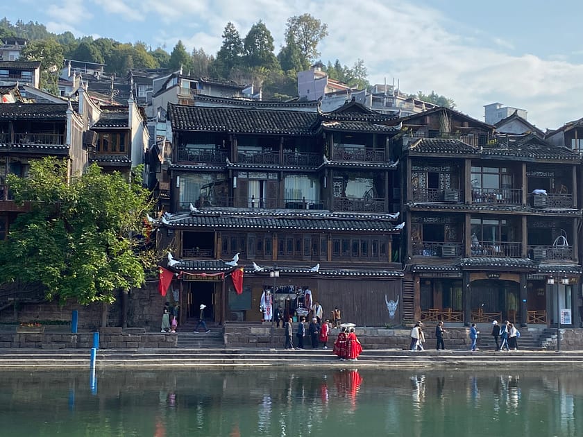 Persones amb vestits vermells tradicionals xinesos a la riba del riu Tuo a Fenghuang