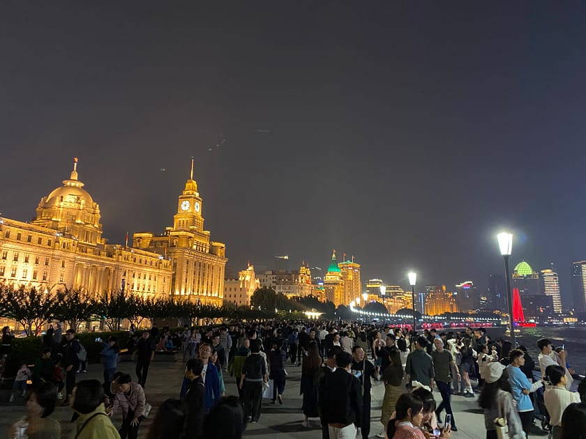 Multitud de persones passejant per Chen Yi Square a Xangai, amb edificis històrics al fons