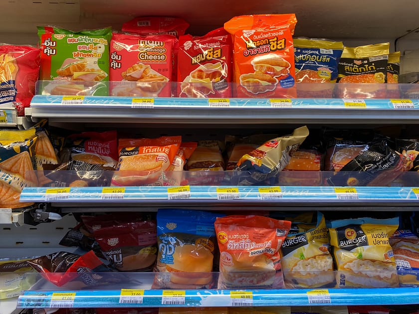 Interior d’un 7-Eleven a Bangkok amb estanteries plenes de productes locals, capturat durant la visita a Huai Khwang i Jodd Fairs.