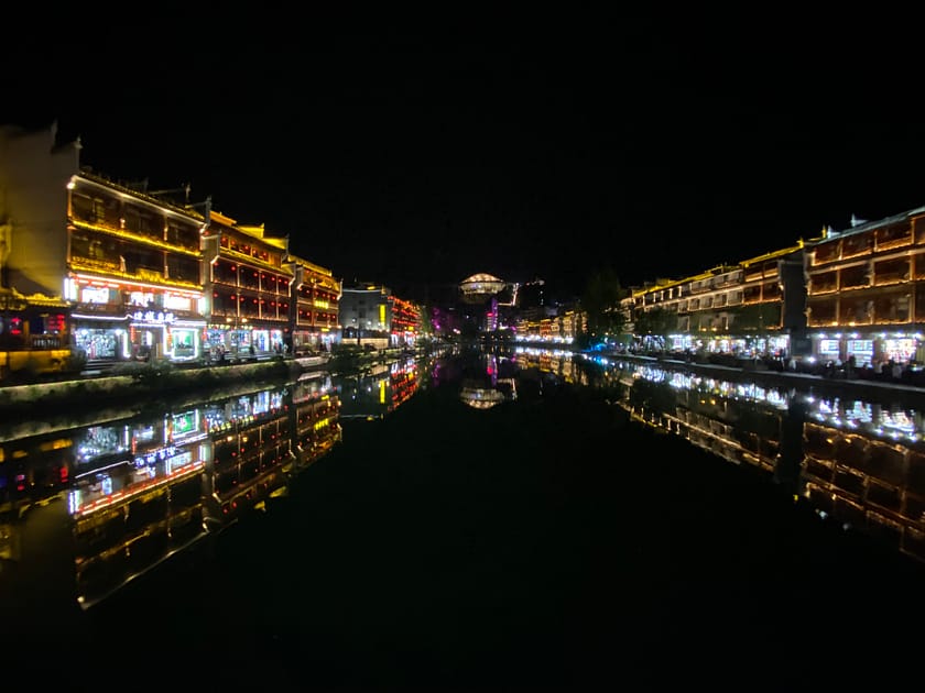 Vista nocturna del riu Tuojiang a Fenghuang amb llums reflectides i cases tradicionals