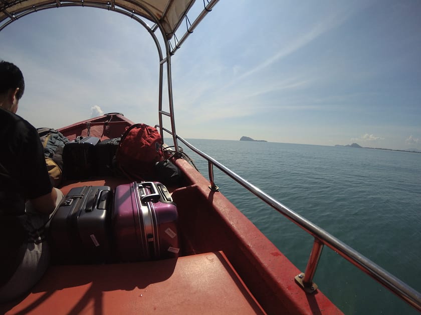 Barques arribant a Perhentian Besar amb viatgers sobre aigües cristal·lines i costa selvàtica