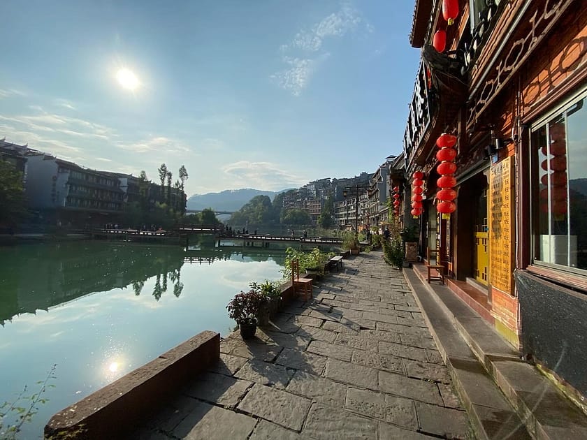 Vista des de la riba del riu Tuo a Fenghuang amb cases penjants i reflexos a l’aigua