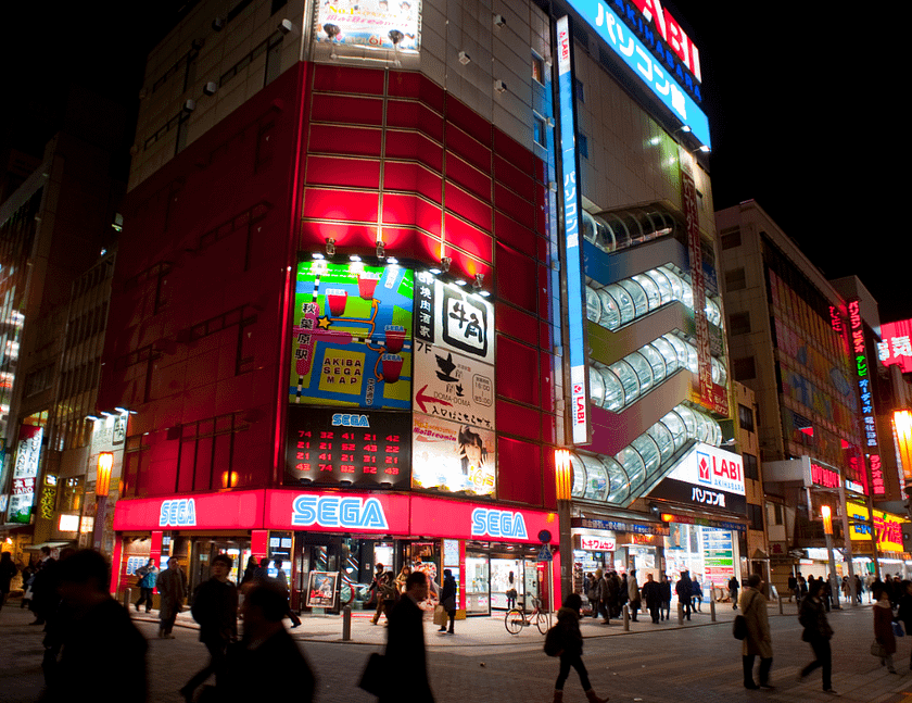 Carrer nocturn d’Akihabara amb neons, edificis comercials i vianants.