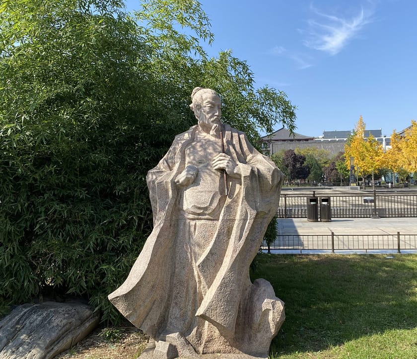Estàtua de Confuci als jardins del temple, amb una pagoda xinesa al fons