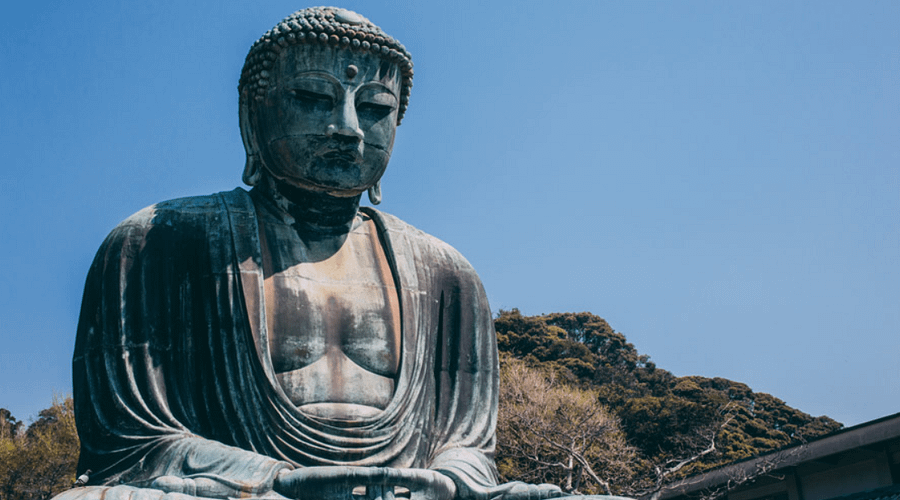 Estàtua del Gran Buda de Kamakura a l’aire lliure, imponent figura de bronze envoltada de visitants i natura.
