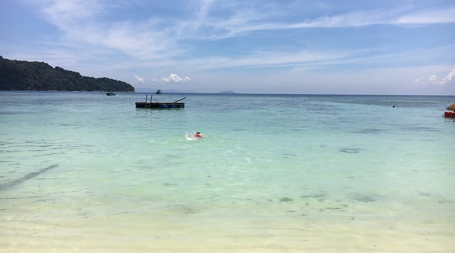 Vista d’una platja tropical a Perhentian Besar amb palmeres, sorra blanca i mar cristal·lí