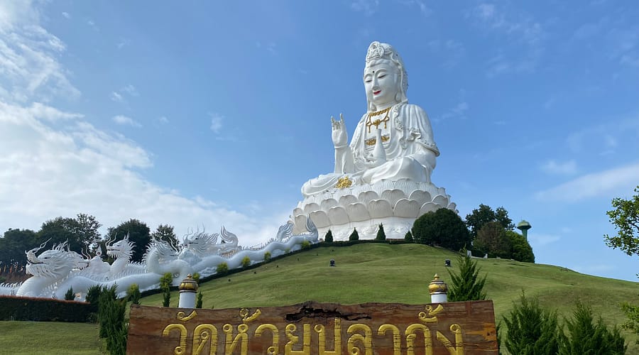 Estàtua gegant de Guan Yin al temple Wat Huay Pla Kang de Chiang Rai, envoltada de paisatge verd i cel clar