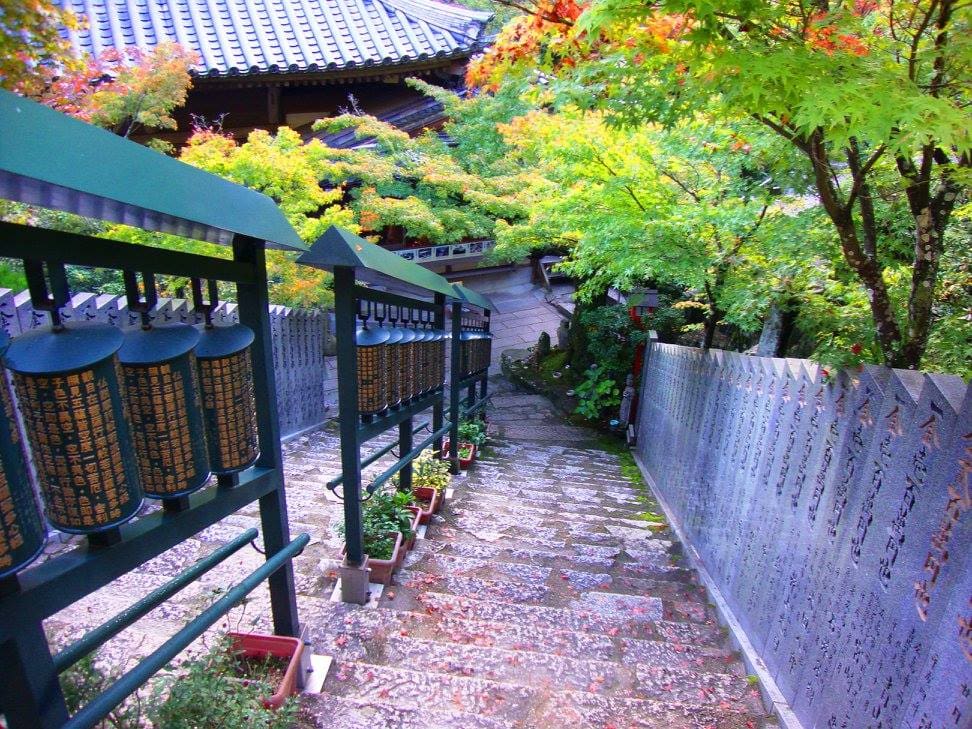 Escales de pedra del Daishō-in a Miyajima amb fileres de molinets budistes metàl·lics que giren al llarg del camí.